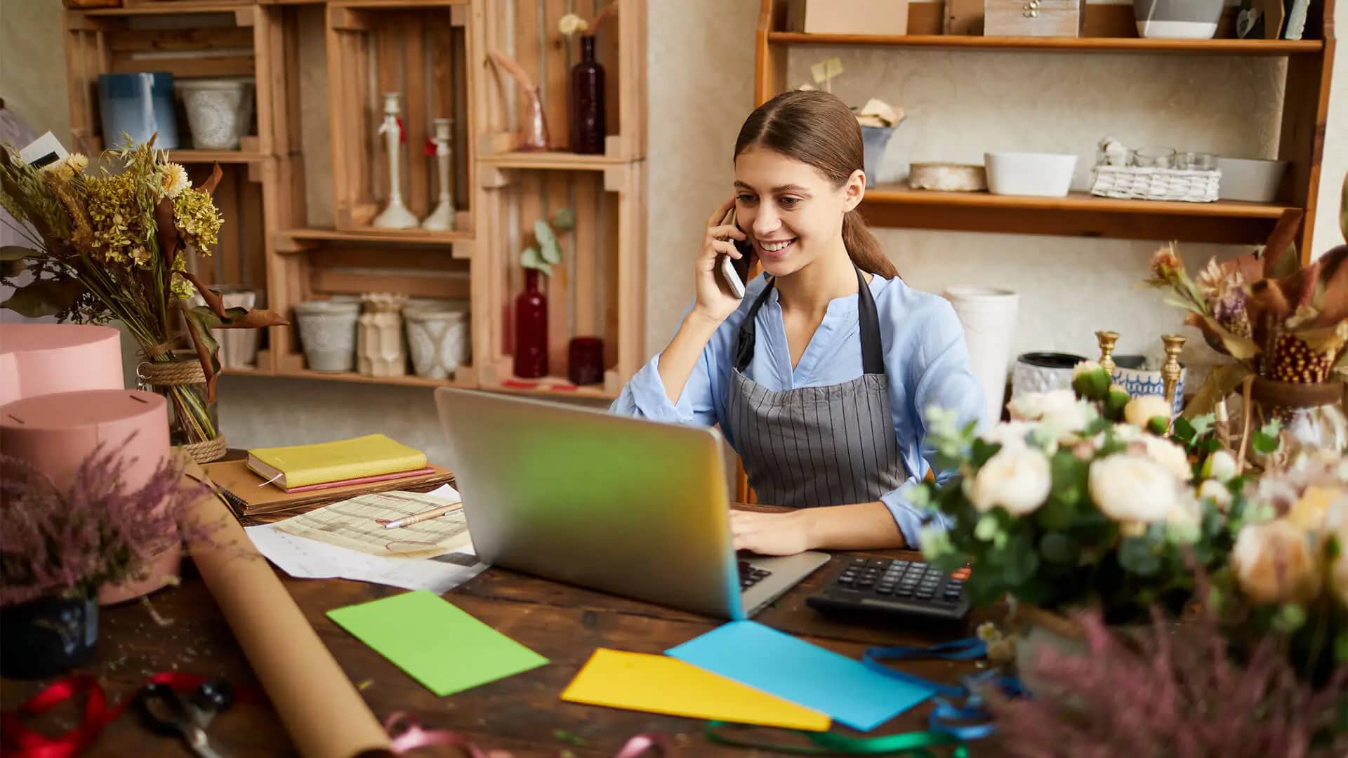 A florist on the phone at her laptop, sorting out her Google Business Profile